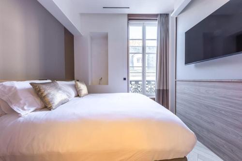 - une chambre avec un grand lit blanc et une télévision à écran plat dans l'établissement Chic 2-Bedroom Haven, à Paris