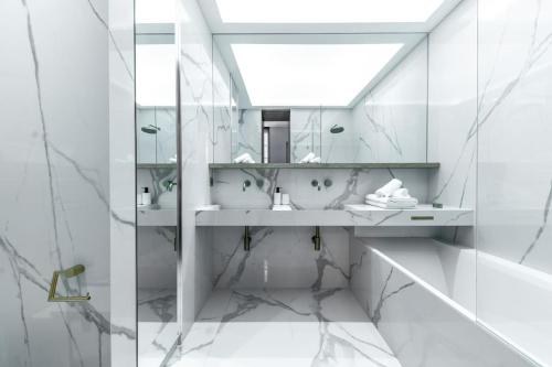 une salle de bain blanche avec deux lavabos et un miroir dans l'établissement Chic 2-Bedroom Haven, à Paris