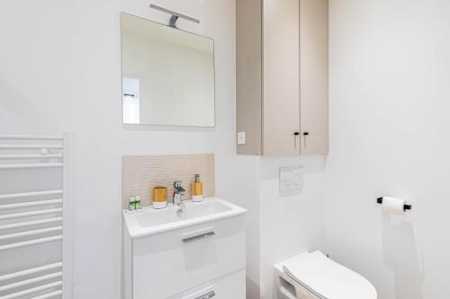 une salle de bain blanche avec un lavabo et un miroir dans l'établissement GuestReady - Charming Stay near Paris, à Malakoff