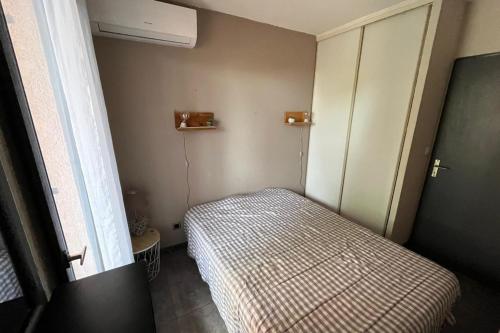 une petite chambre avec un lit et une fenêtre dans l'établissement Cosy flat with pool and sea view, à Saint-Cyprien