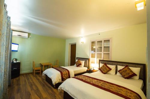a hotel room with two beds and a table at Hotel Harmony & Little Bites Bistro in Pātan