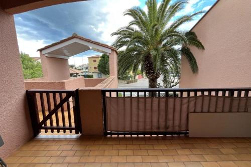 une porte en bois menant à une maison avec un palmier dans l'établissement Cosy flat with pool and sea view, à Saint-Cyprien