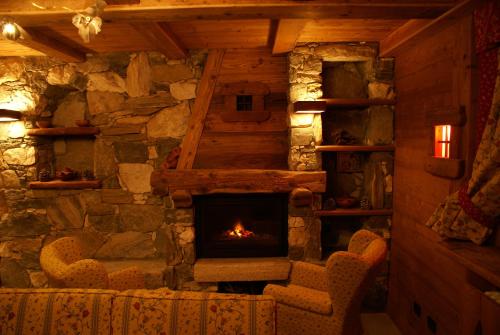 a stone fireplace in a room with two chairs at Hotel Tersiva in Valtournenche