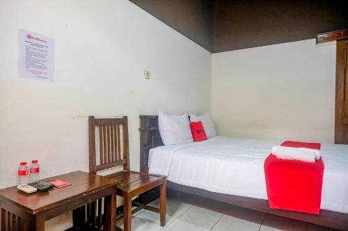 a bedroom with two beds and a table and a desk at RedDoorz at Mayang Garini 2 Borobudur in Magelang