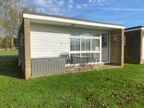 a tiny house with a patio and a table at Chalet 59 Florida Holiday Park Hemsby in Hemsby