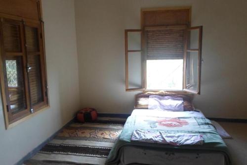 a bedroom with a bed in a room with a window at Ryad-IGRANE in Ouarzazate