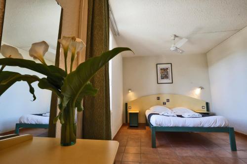 a hotel room with two beds and a potted plant at Village vacances Le Hameau des Oliviers in Vaison-la-Romaine