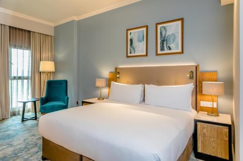 a bedroom with a large bed and a blue chair at Southern Sun Sandton in Johannesburg