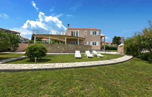 a house with two lawn chairs and a building at Stunning Apartment In Ugljan With Wifi in Ugljan