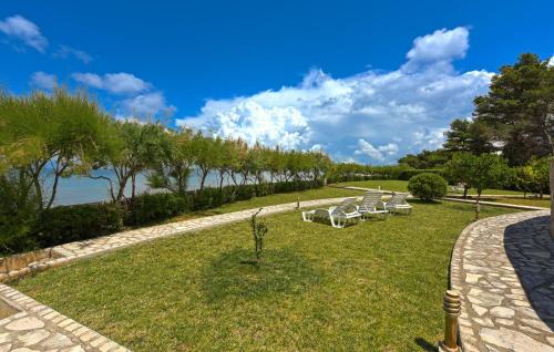 a row of white lounge chairs in a park at Stunning Apartment In Ugljan With Wifi in Ugljan