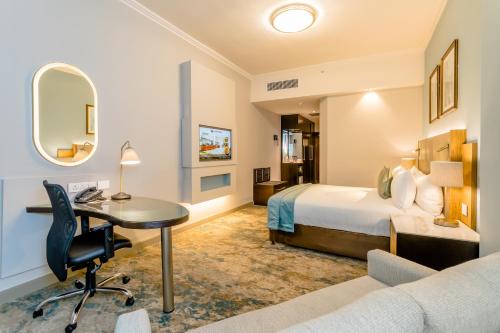 a hotel room with a bed and a desk at Southern Sun Sandton in Johannesburg