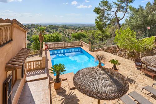 an outdoor swimming pool with an umbrella and chairs at Finca Puig de Sa Figuera in S'Horta