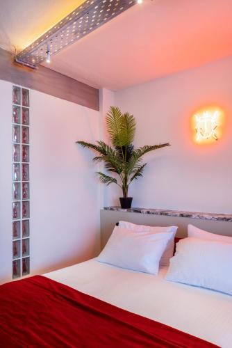 a bedroom with a white bed and a potted plant at The Newel Metaxourgeio in Athens