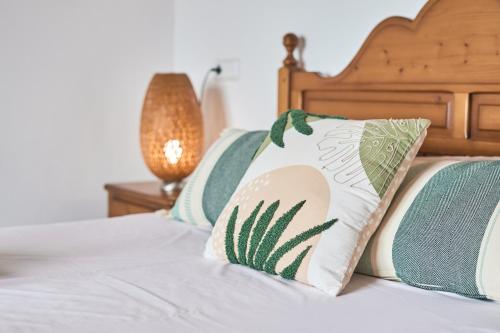 a bed with green and white pillows on it at Finca Puig de Sa Figuera in S'Horta