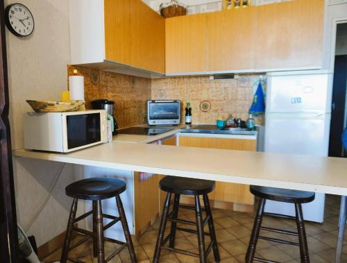 une cuisine avec un comptoir et deux tabourets de bar dans l'établissement L'amphitrite Vue mer Proche Accès direct plage, au Barcarès