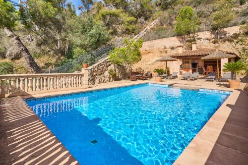 a swimming pool with blue water in front of a house at Finca Puig de Sa Figuera in S'Horta