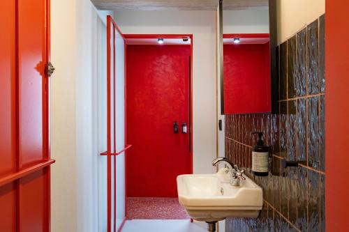 a bathroom with a red door and a sink at The Newel Metaxourgeio in Athens