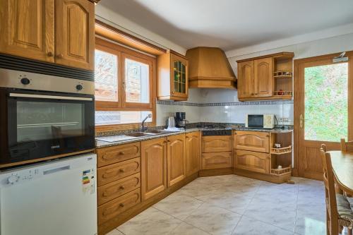 a kitchen with wooden cabinets and a white refrigerator at Finca Puig de Sa Figuera in S'Horta