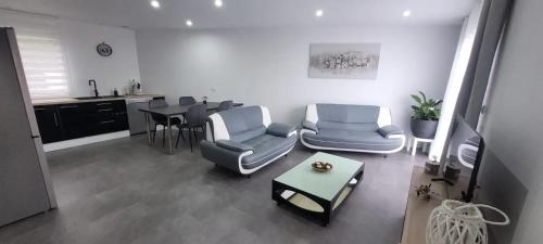 a living room with chairs and a table and a kitchen at Maison confortable à Casson, 60 m², bien équipée in Casson