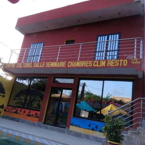 a red building with a sign on the side of it at Auberge Africa Thiossane in Saly Portudal
