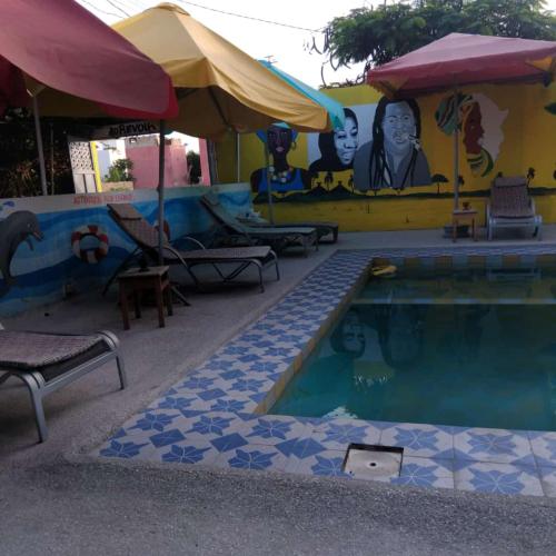 a pool at a resort with a painting on the wall at Auberge Africa Thiossane in Saly Portudal