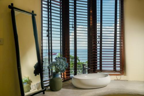 a bathroom with a large window with a tub in front at Nangyuan Island Dive Resort in Koh Tao