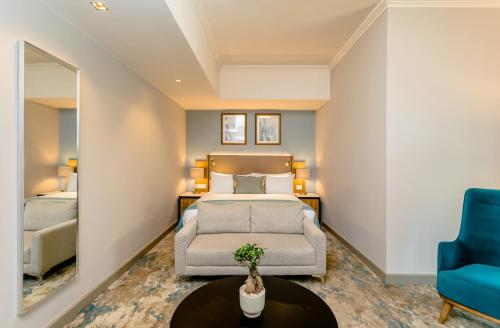 a bedroom with a bed and a blue chair at Southern Sun Sandton in Johannesburg