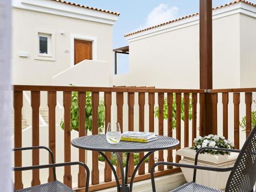 a table on a balcony with a glass of wine at Grecotel Marine Palace & Aqua Park in Panormos Rethymno