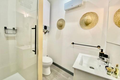 une salle de bain blanche avec des toilettes et un lavabo dans l'établissement Le Kozy - coeur ville - clim, à Nîmes