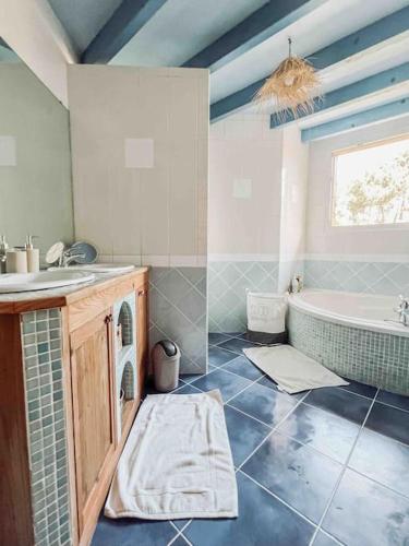 une salle de bain avec un lavabo et une baignoire dans l'établissement Villa Charme et Nature pres de l Ocean, à Labenne