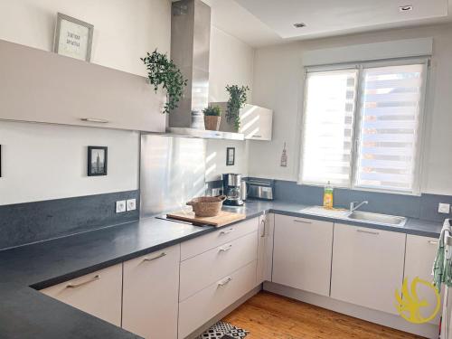 une cuisine avec des armoires blanches, un évier et une fenêtre dans l'établissement Duplex Élégant et Spacieux, à Lens