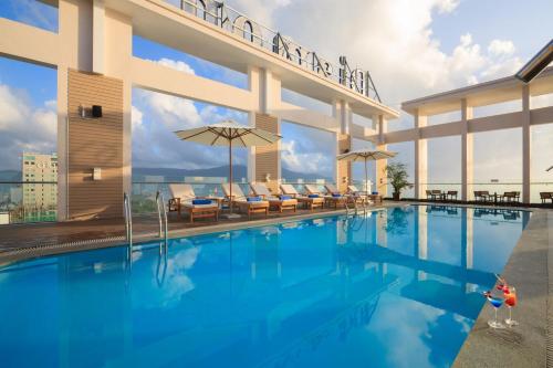 a pool at a hotel with chairs and umbrellas at Diamond Sea Hotel in Da Nang