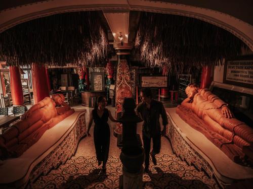 a group of people walking through a room with beds at House of Tugu, Old Town Jakarta in Jakarta