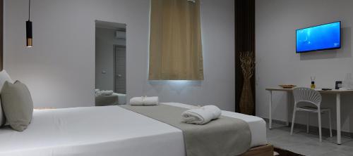 a white bedroom with a bed and a table and a tv at Hotel Movida in Casoria