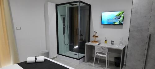 a bathroom with a shower and a desk with a television at Hotel Movida in Casoria