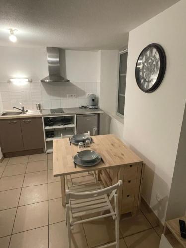 une cuisine avec une table et une horloge au mur dans l'établissement Studio rénové au calme, à Dole