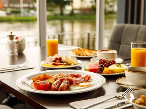 a table topped with plates of breakfast food and orange juice at Sunday London Staines-upon-Thames Heathrow T5 in Staines