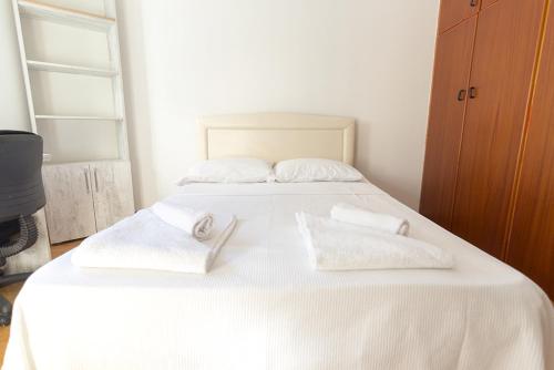 a white bed with two white towels on it at Peanut House by HolidayKeys in Kérynia