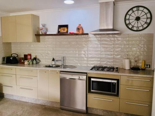 a kitchen with a stove and a sink and a clock at Manuka Getaway in Maleny