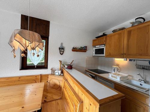 une cuisine avec des armoires en bois et un comptoir dans l'établissement CYBELE C1 appartement proche village et pistes, à La Clusaz
