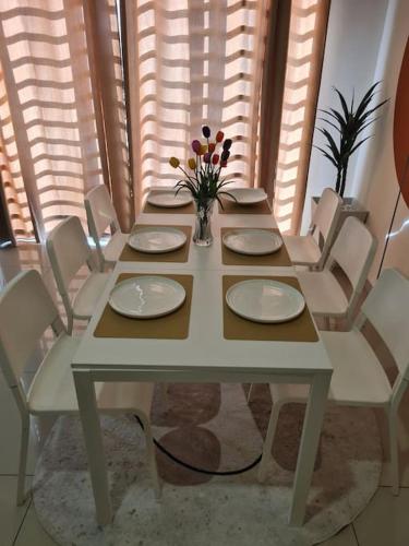 a table with plates and a vase of flowers on it at UniVilla- Ideal Family Home for 18pax in Gelugor