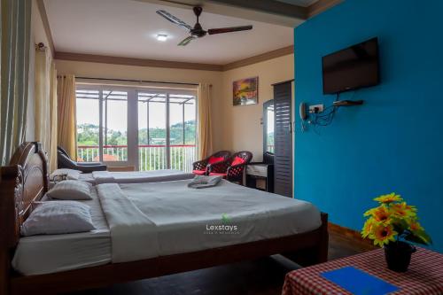 a bedroom with a bed with a blue wall at Vijaya Deepa Guest House by LexStays in Coonoor