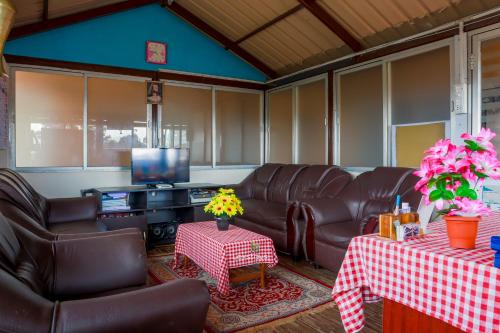 a living room with leather furniture and a flat screen tv at Vijaya Deepa Guest House by LexStays in Coonoor