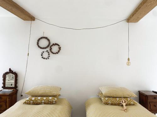 a bedroom with two beds and a wall with clocks at Maison Galop Marin in Saint-Côme-du-Mont