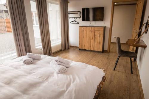 a bedroom with a bed and a chair and a television at Casa Delia Toplita in Topliţa