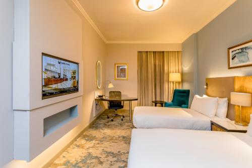 a hotel room with two beds and a tv at Southern Sun Sandton in Johannesburg
