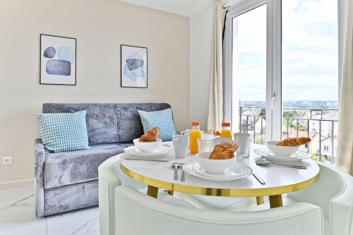 - un salon blanc avec une table et de la nourriture dans l'établissement Appartement proche de Paris - Gagny - III, à Gagny