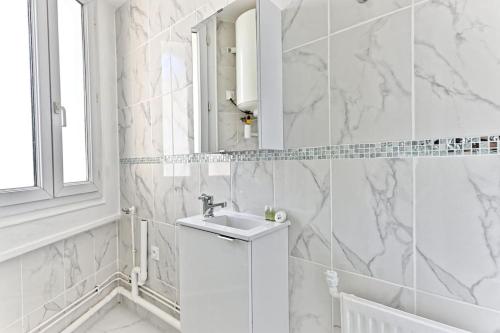 une salle de bain blanche avec un lavabo et un miroir dans l'établissement Appartement proche de Paris - Gagny - III, à Gagny
