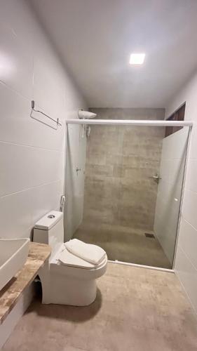 a white bathroom with a shower and a toilet at Casarão Suítes Maragogi in Maragogi