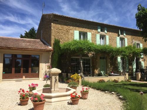 a house with a fountain in front of a building at Fontaine des Magnarelles in Althen-des-Paluds